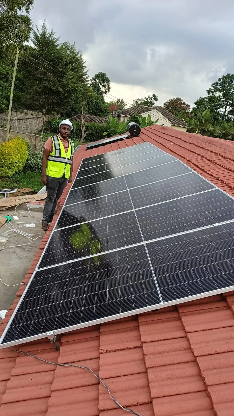 Engineer on a tiled roof beside a newly installed solar array